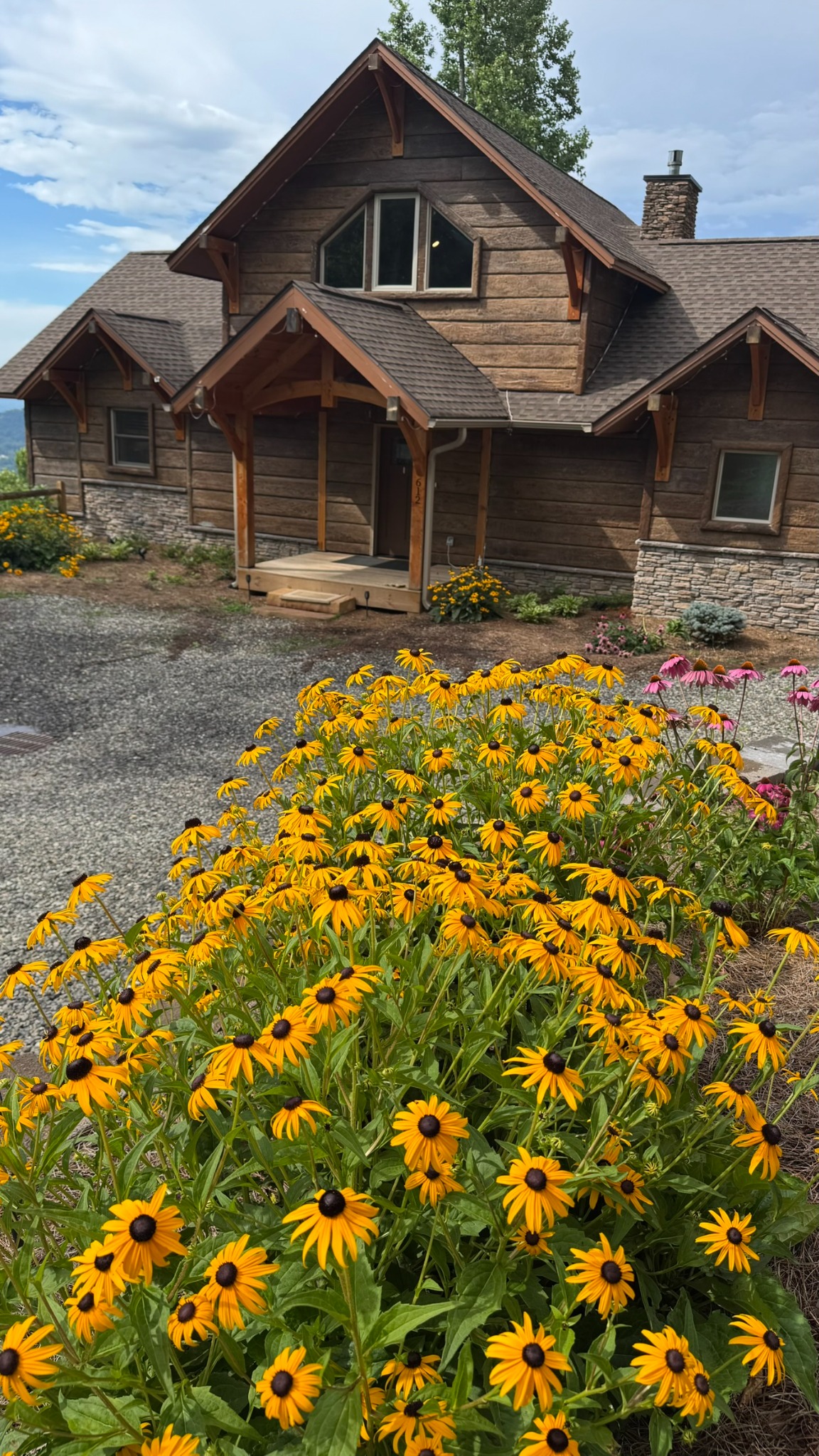 Flowers at the front door · Bright garden blooms line the approach to the timber-framed front entrance.