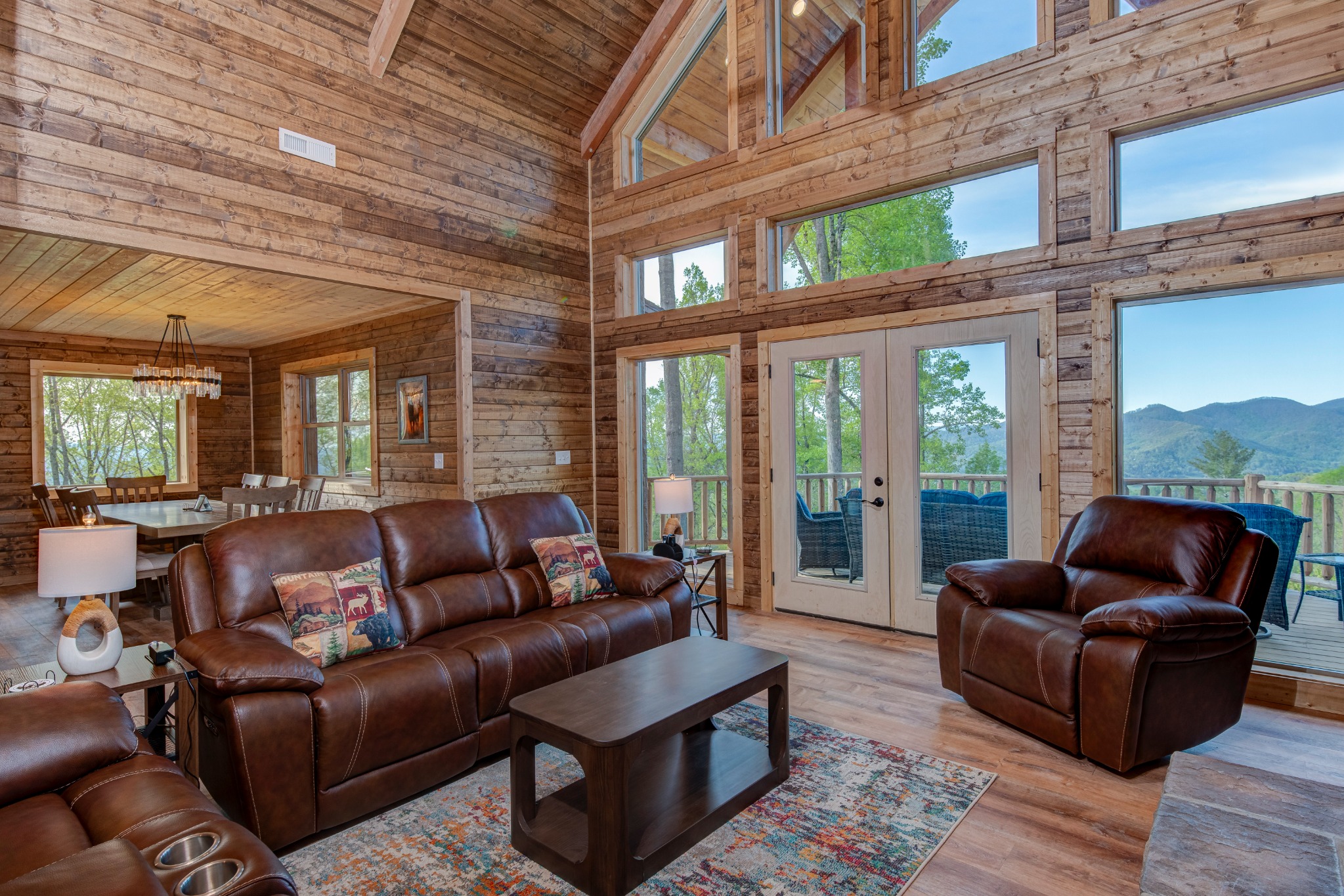 Great room with a view · Relax in leather seating beneath the timber ceiling, with mountain views through the tall windows and deck doors.