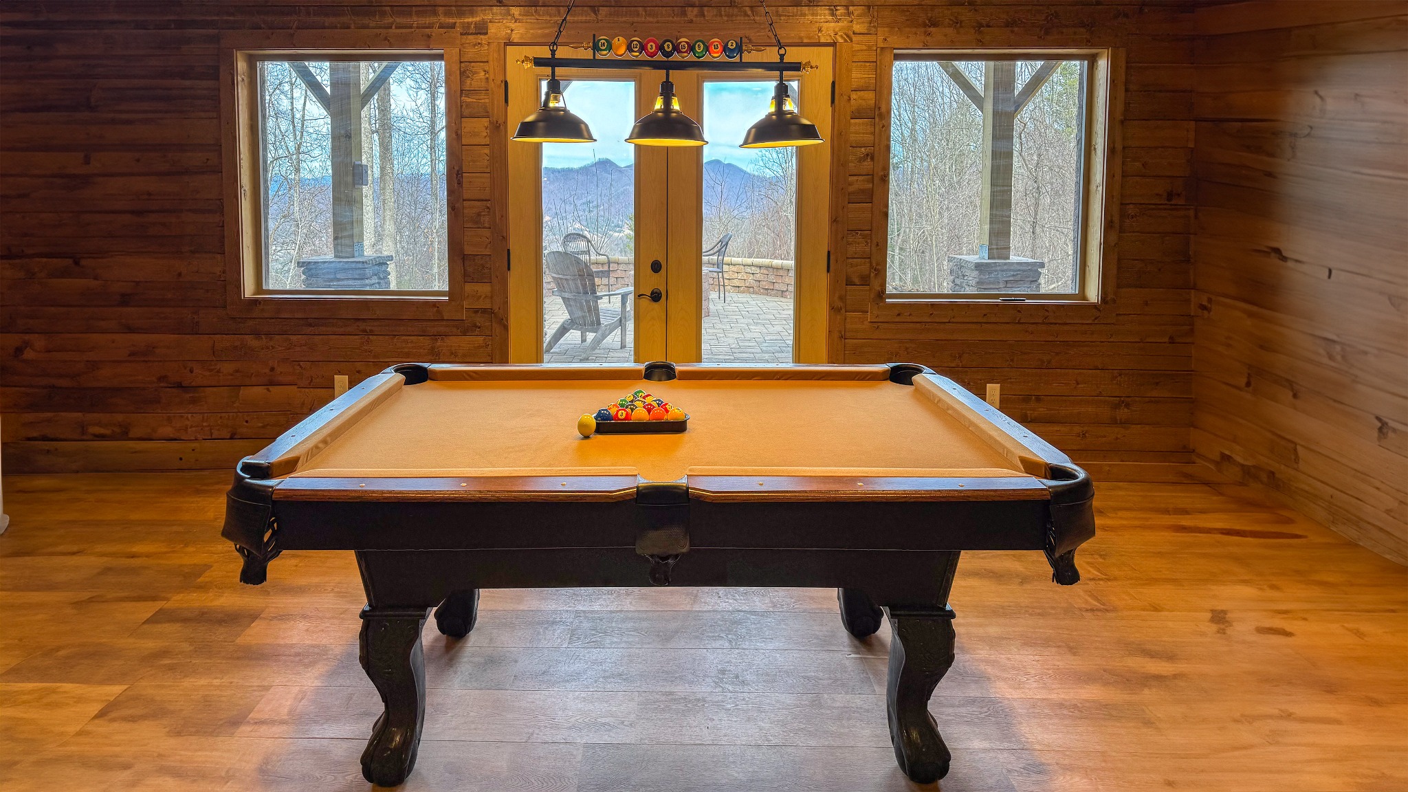 A little friendly competition · Enjoy a game of pool in the wood-paneled recreation room, with mountain scenery visible through the glass doors.